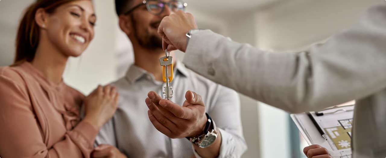 Casal recebendo as chaves de um imóvel novo após compra, simbolizando aquisição de casa própria