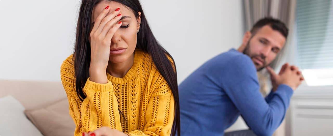 Casal em processo de separação, com mulher de costas e homem ao fundo, representando conflito familiar e divórcio